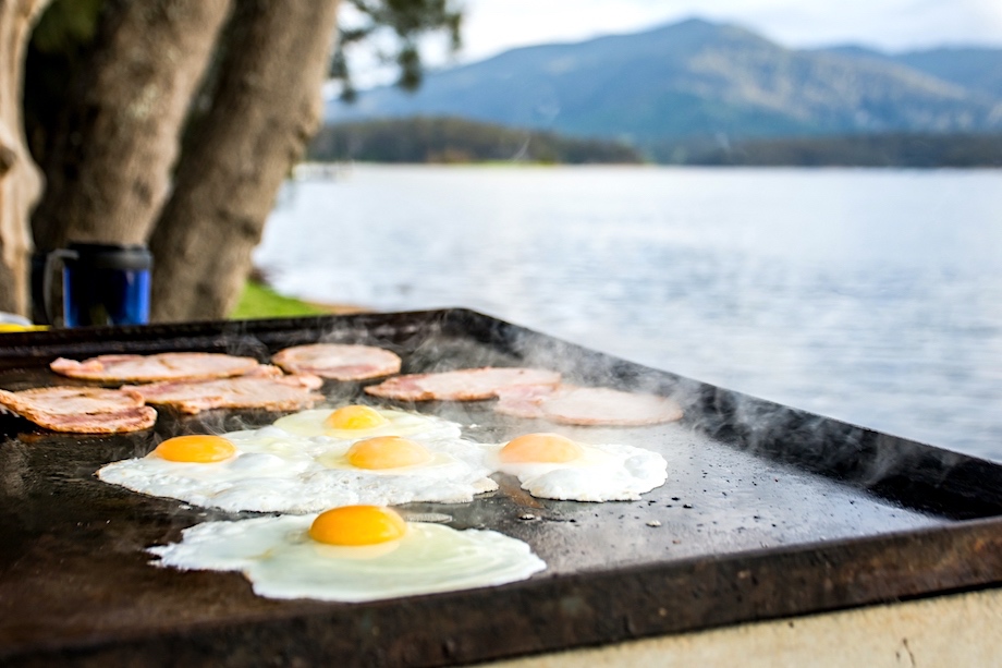 Breakfast Camp Cooking, Grilling Eggs And Bacon On The Bbq Plate With Beautiful Nature Landscape On