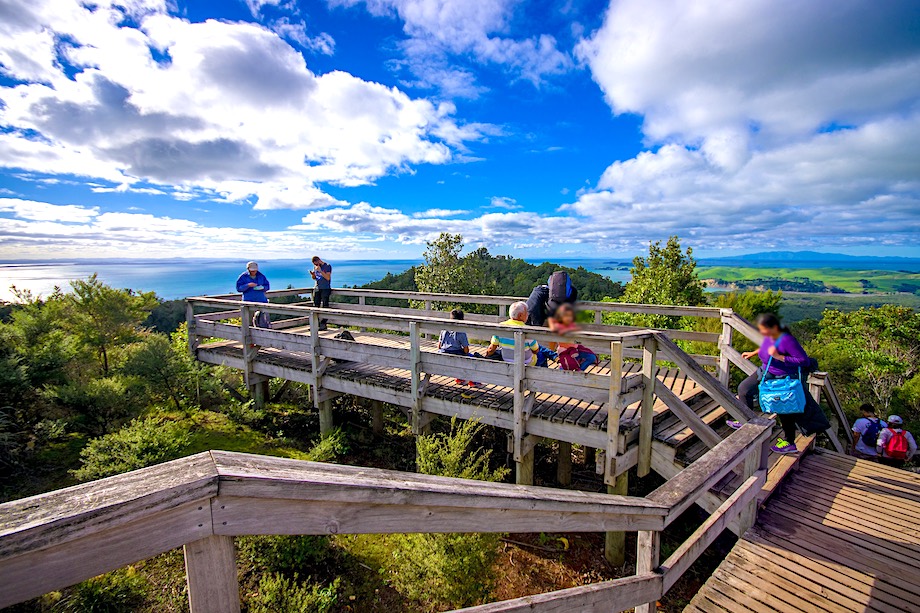 AUCKLAND, NEW ZEALAND- MAY 12, 2017: Unidentified people enjoying the beautiful view from top in the mountain in Rangitoto Island walking in wooden paths, New Zealand in a sunny day.