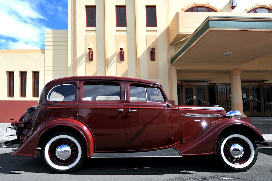 An old car parked outside a cinema that was built in Art Deco style following a major earthquake in 1931. Napier, New Zealand.