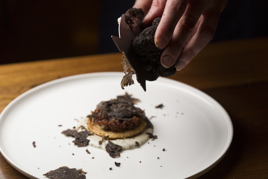 Celebrate truffles in Canberra. Image of a womans hand lifting truffles off a plate. 