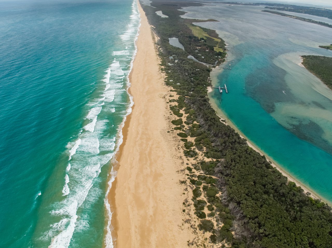 Birds eyes image of the Ninety Mile Beach. blue waters on either side of a a sand dune and forest