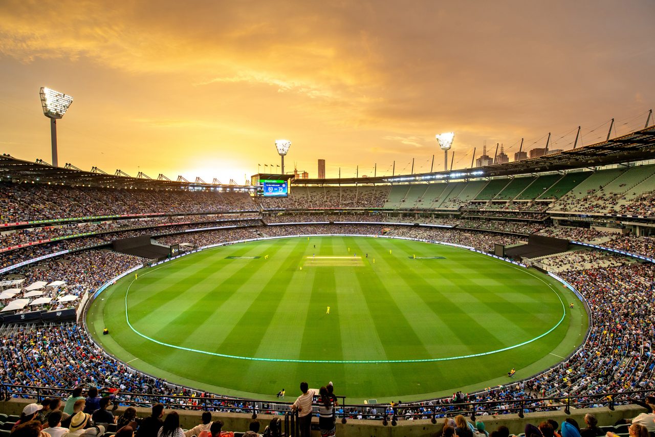 Melbourne Cricket Ground at sunset. Lights on with a cricket game being played