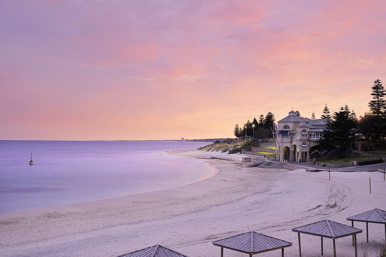 Cottesloe Beach at sunset with a building in the background.