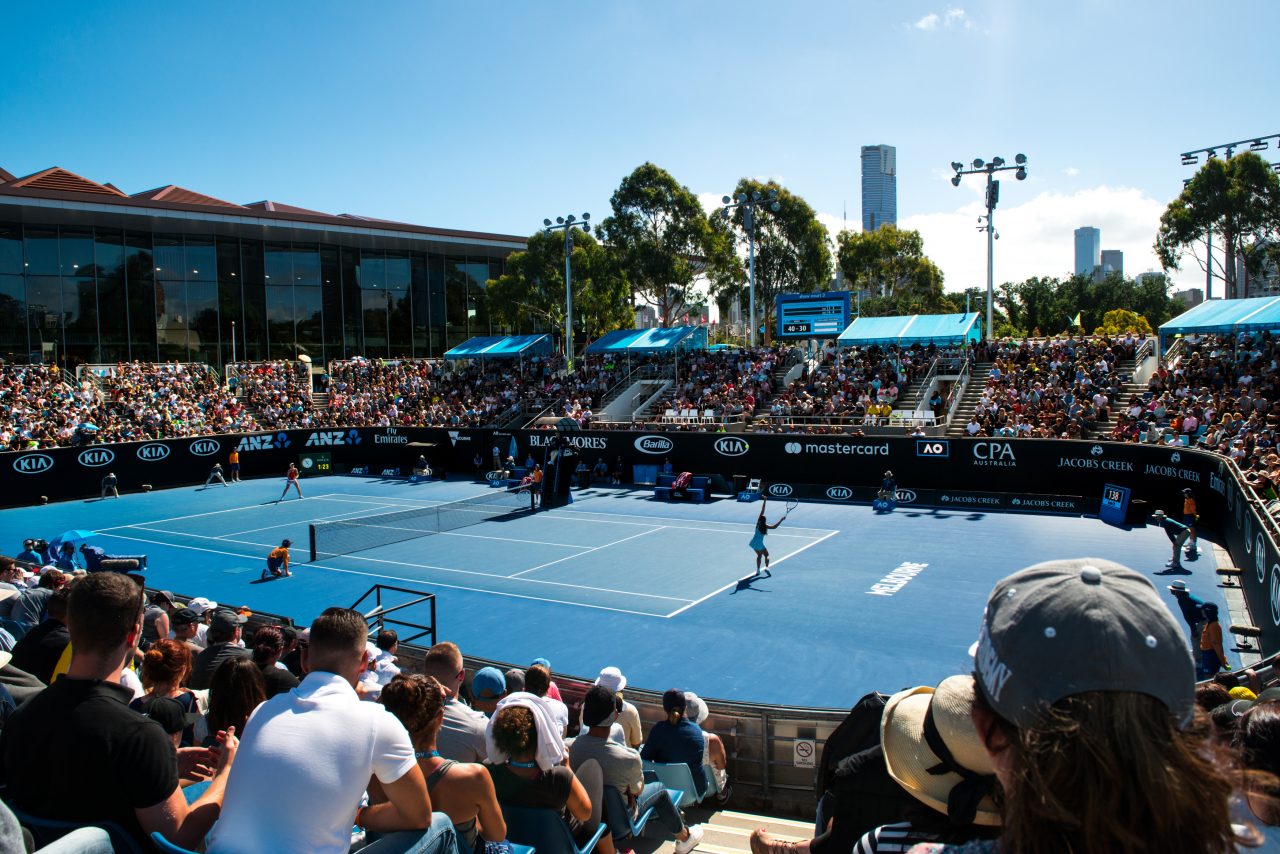 Two players playing tennis at the Australian Open in the back courts.