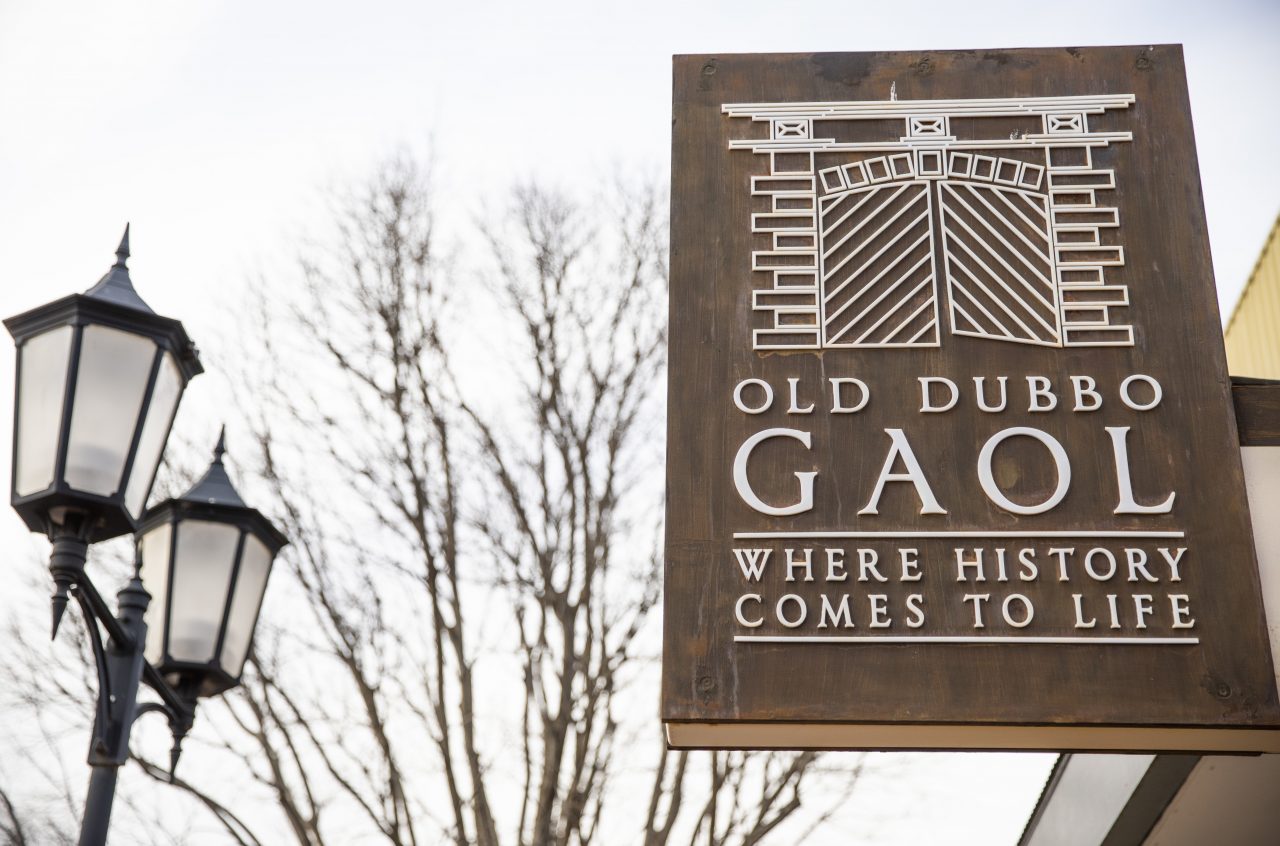 image of the entrance sign from the Old dubbo Gaol with trees and light posts in the background