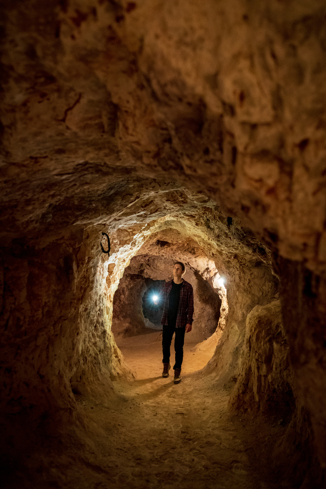 A man with a flashlight taking a tour of an underground opal mine