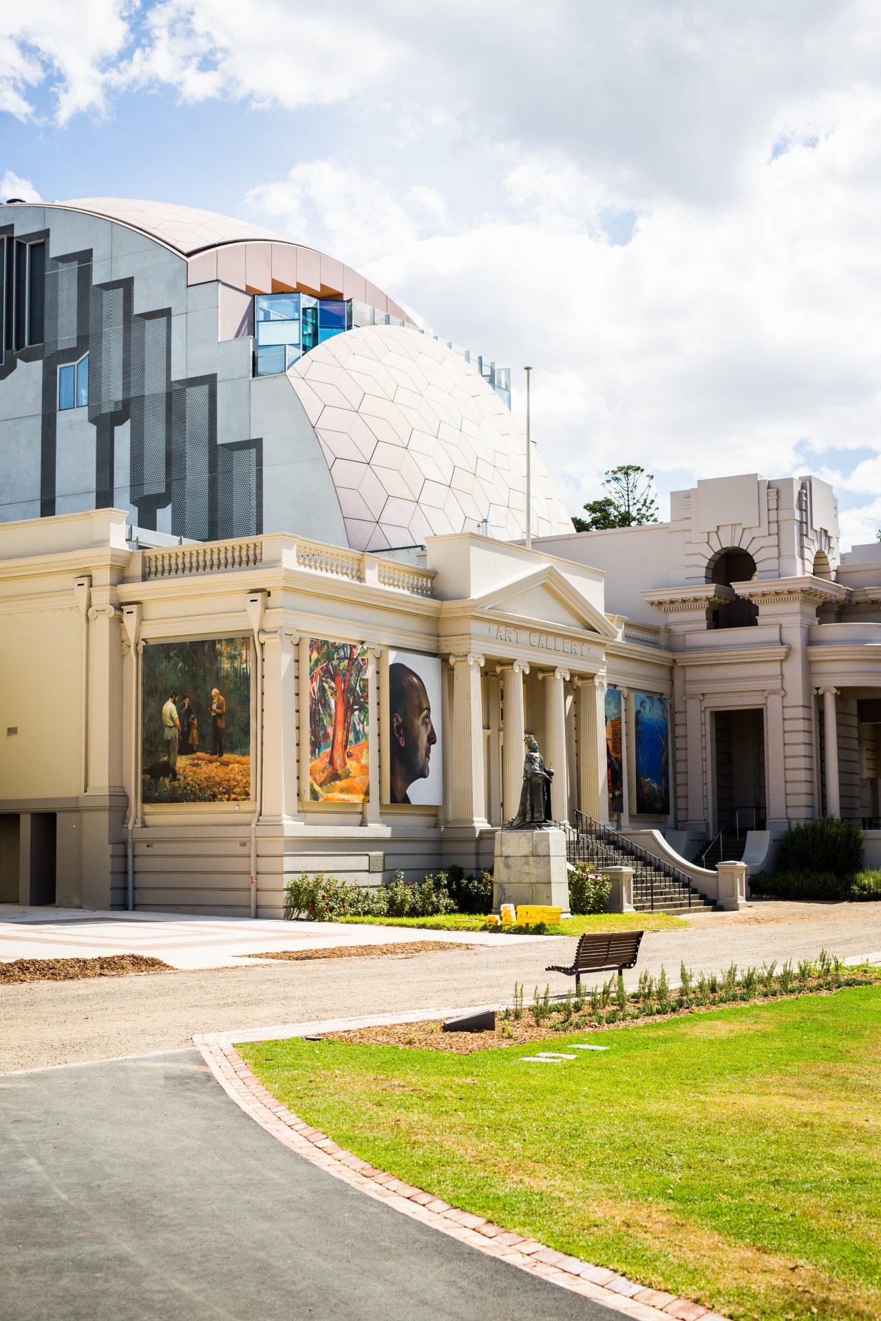 Side angle shot of the Geelong Art Galley. On the exterior of the building, their are huge images of artwork displayed on them.