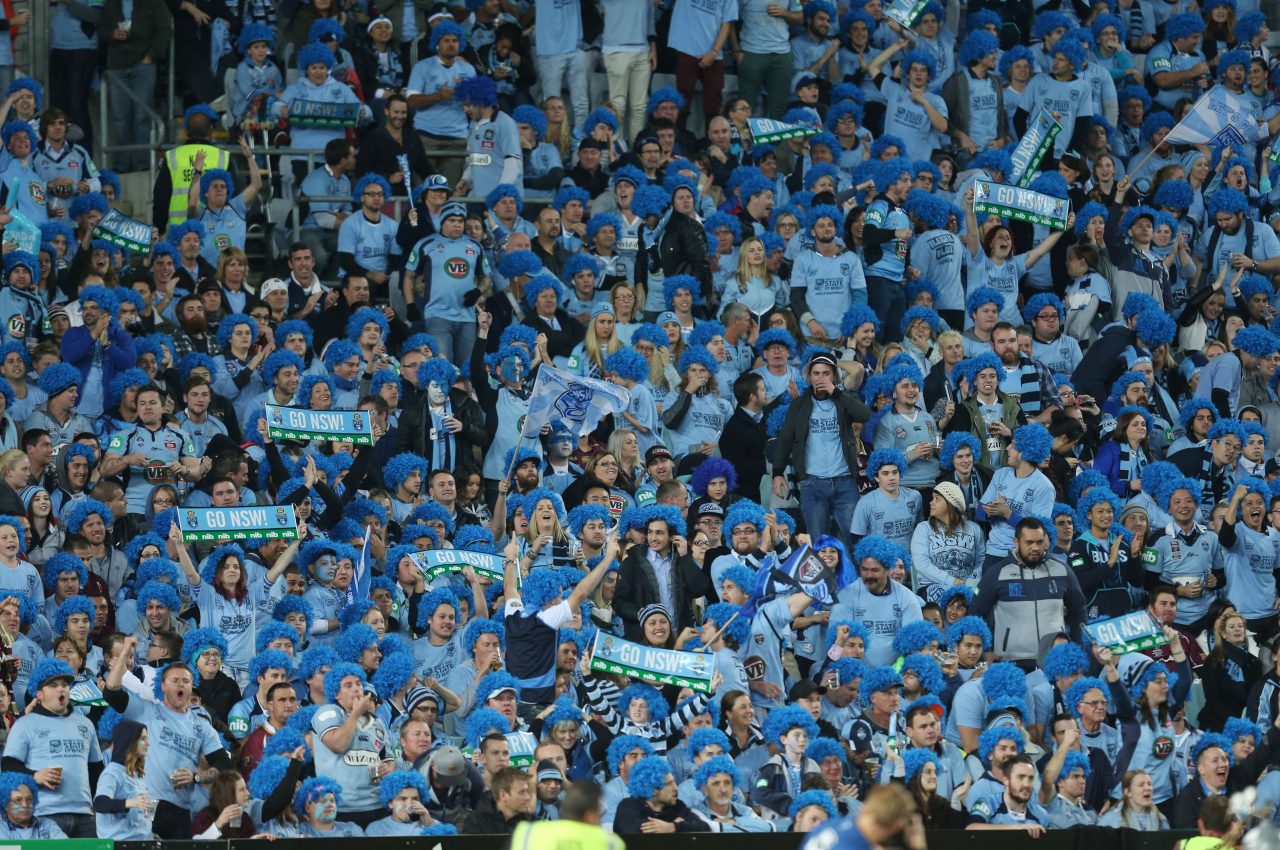 a crowd of people cheering on sport at a stadium. All people wearing blue to support their team