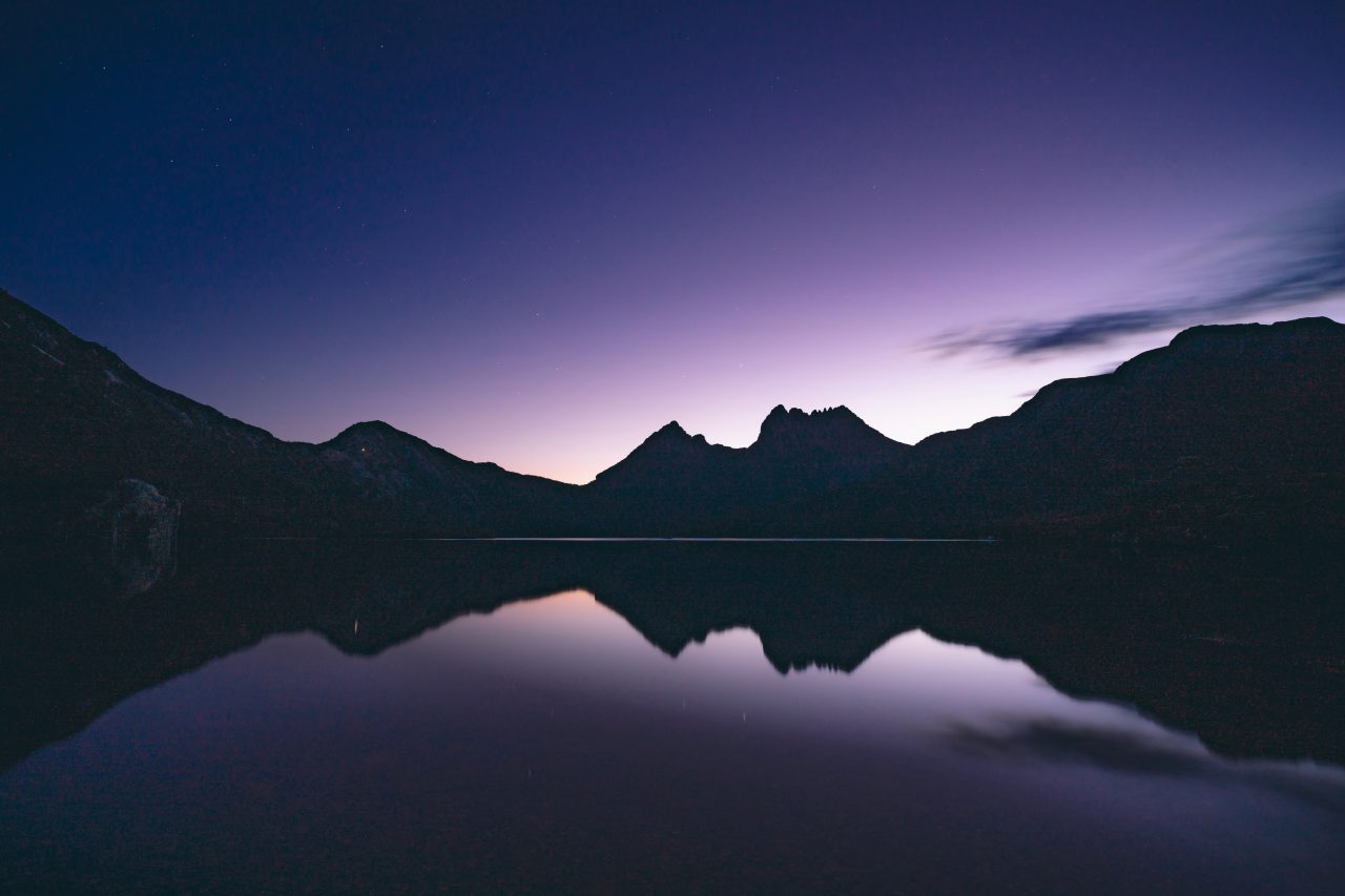 Image of a lake with a mountains in the background at dusk.