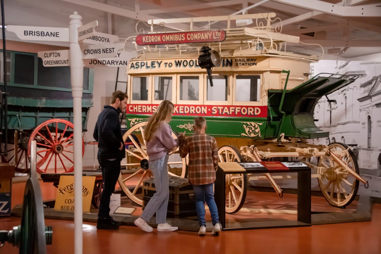 Family looking at an old stage coach at the Cobb+Co Museum
